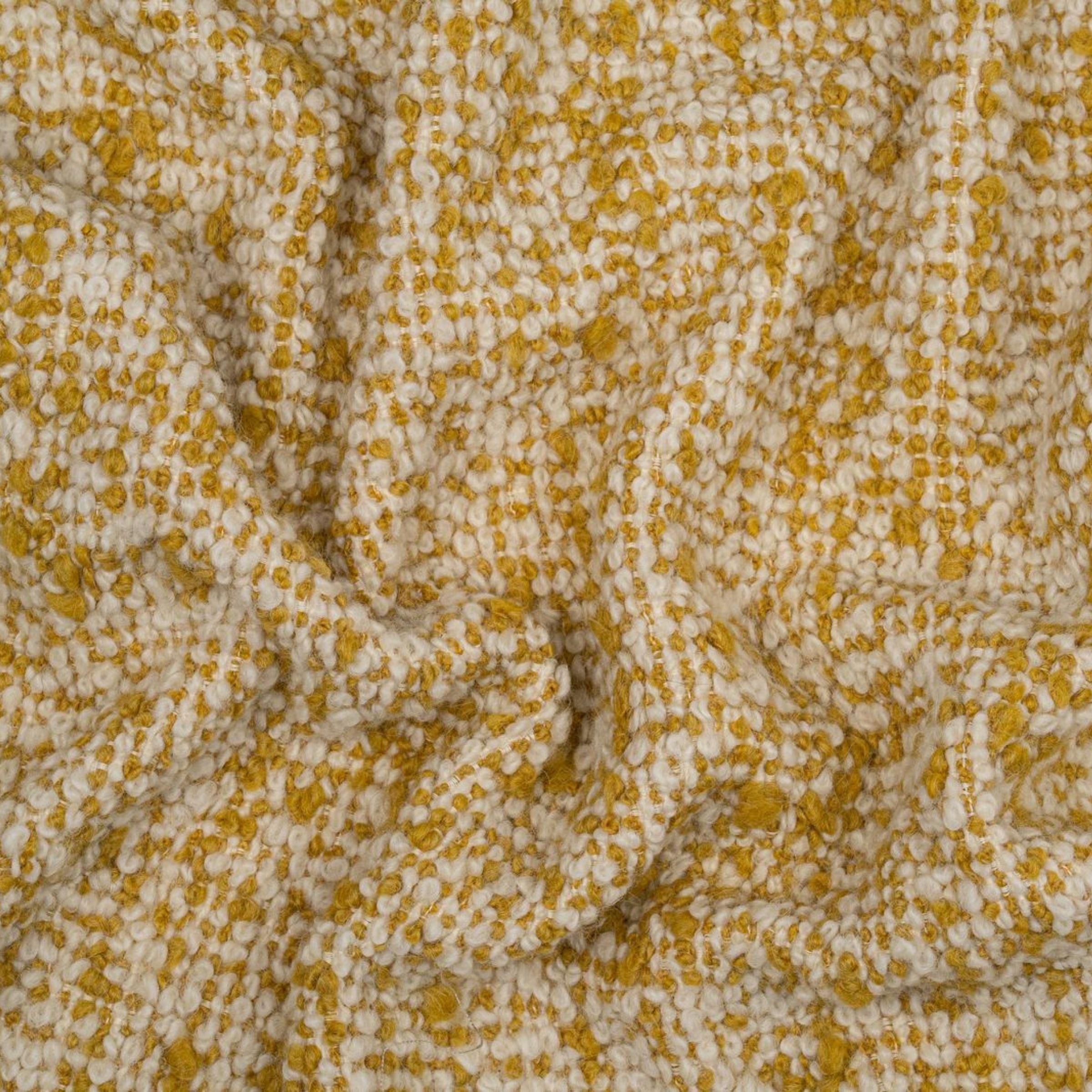 Textured boucle upholstery with a pattern of small yellow and white dots with subtle folds 