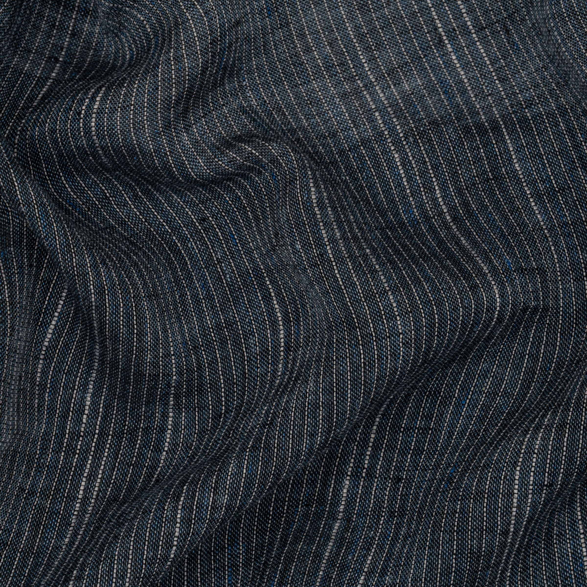 Close-up of dark denim fabric with subtle pinstripes and wavy folds