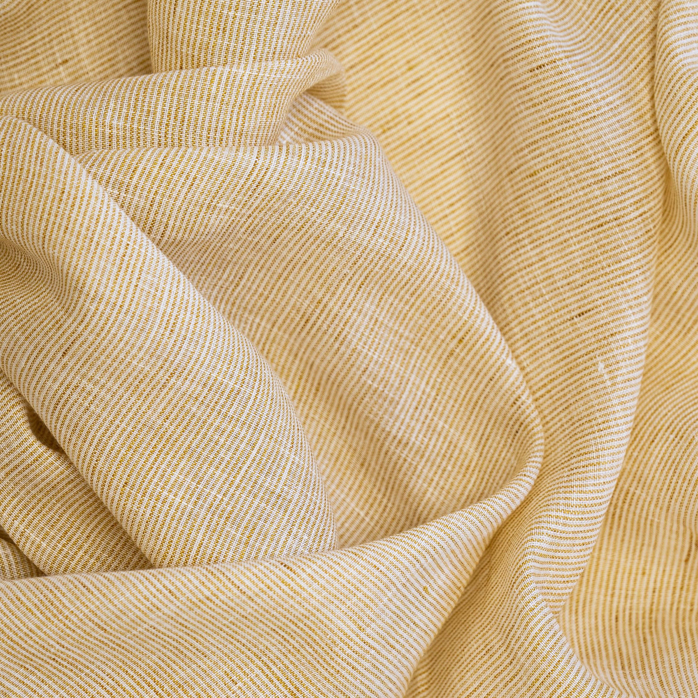 Textured yellow and white striped patterned fabric with large natural folds