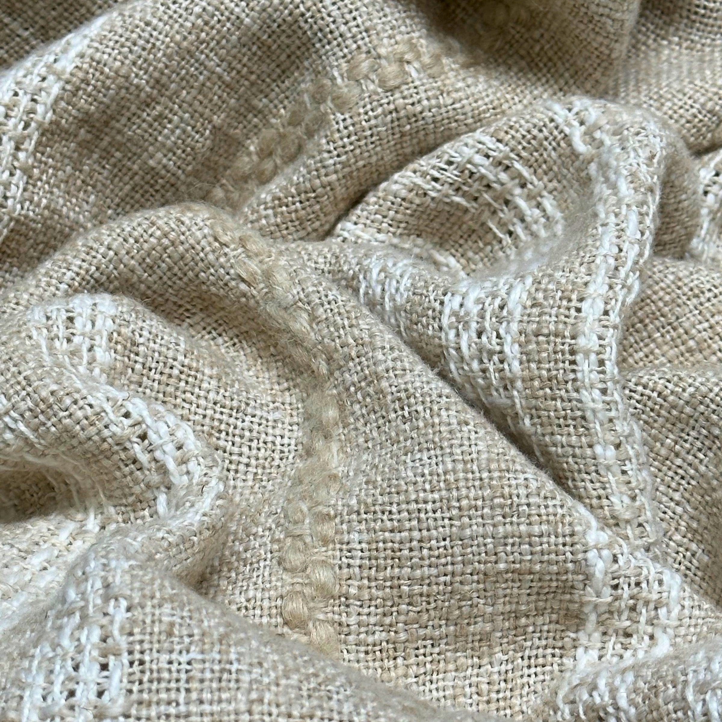 Close-up of textured beige fabric with white stripe detailing and wavy folds