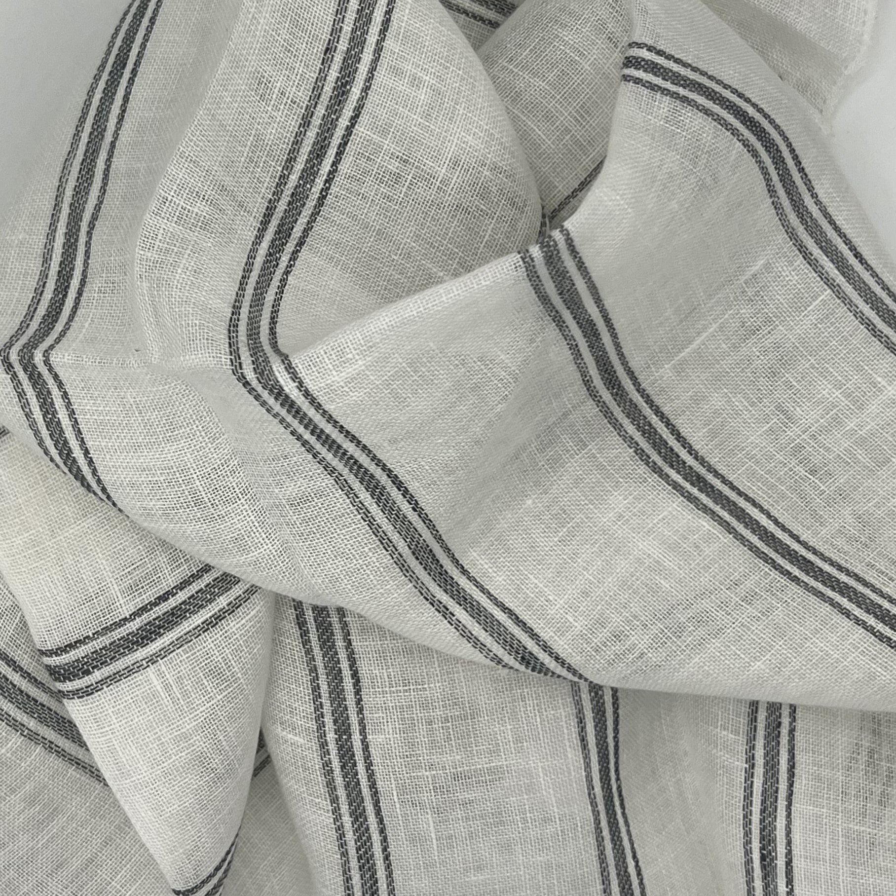 Mykonos fabric is an off-white linen fabric, with a thin charcoal gray colored stripe and large folds