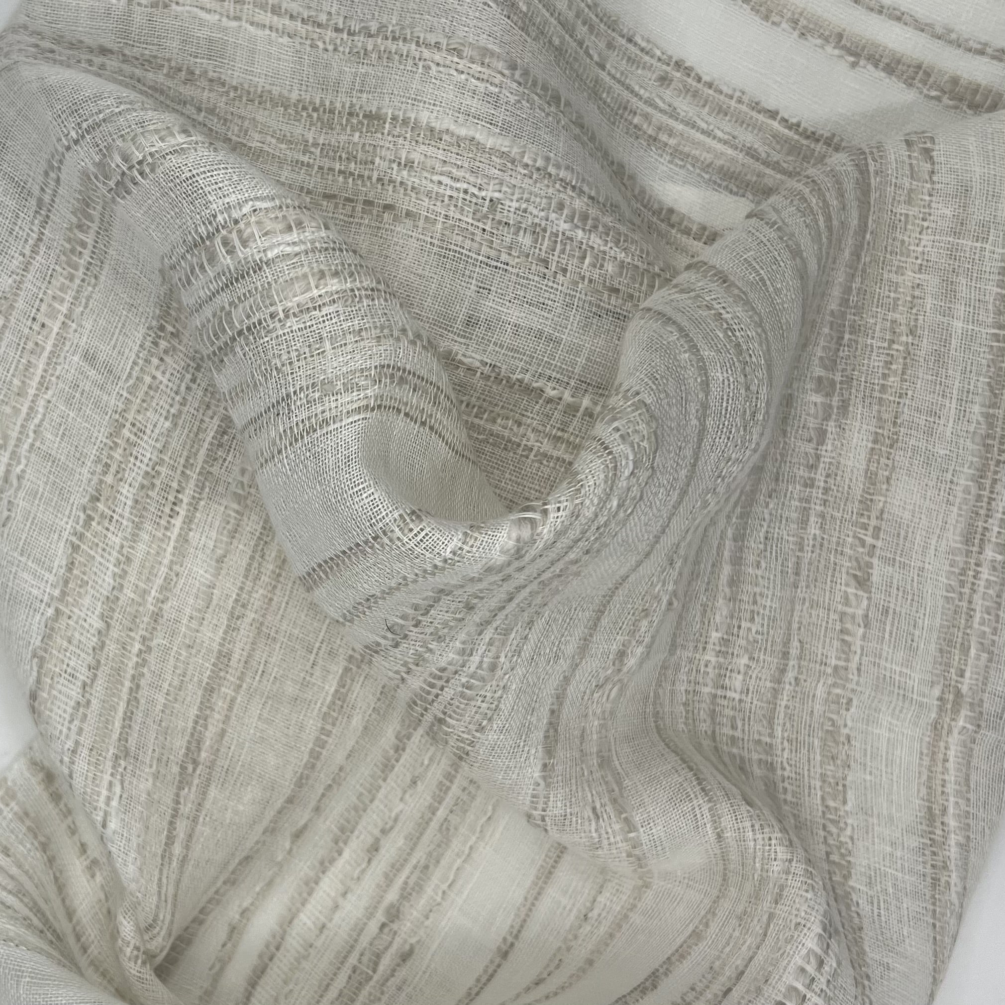 Close-up of white fabric with a neutral color stripe and large twisted folds