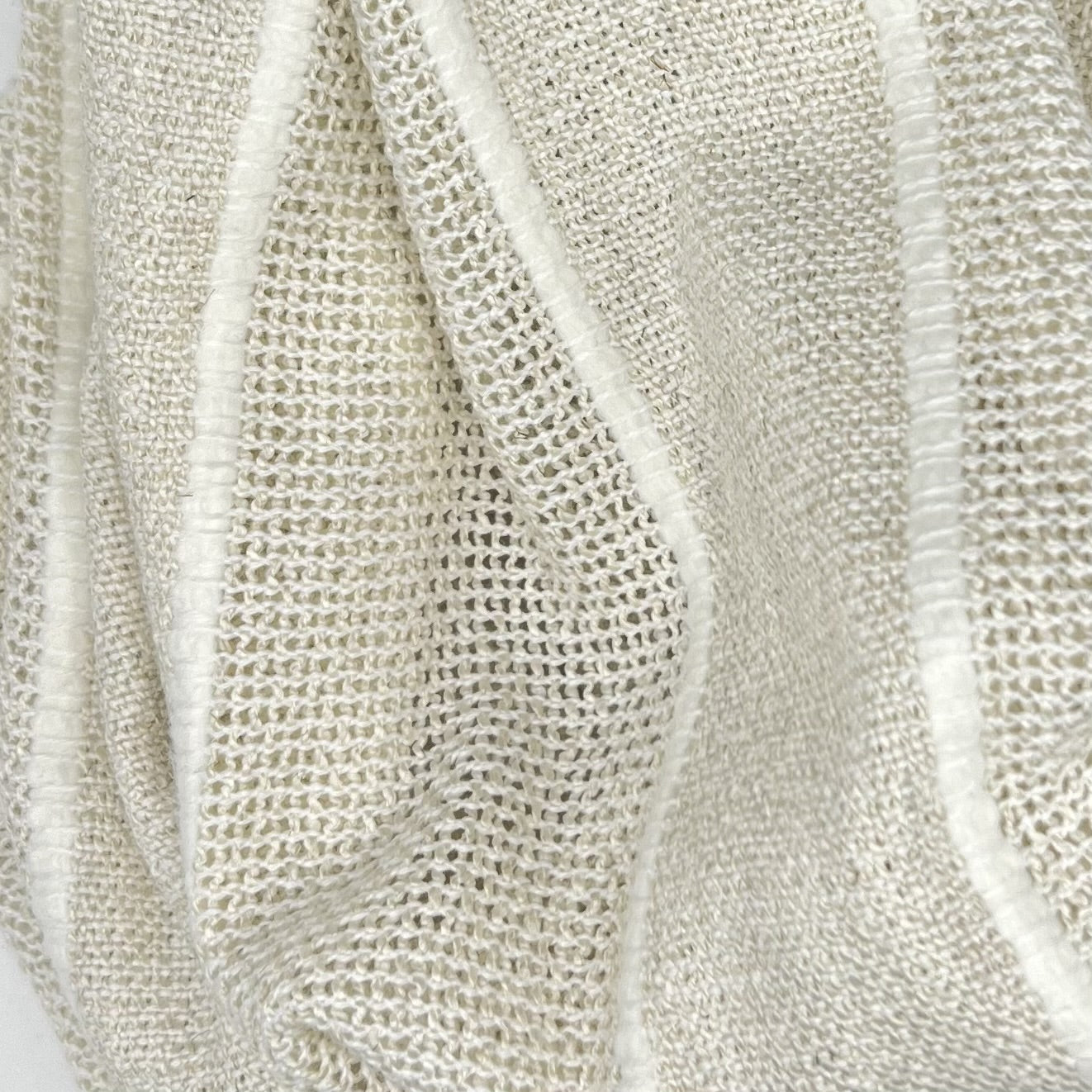 Close-up of textured beige fabric with white striped and vertical folds
