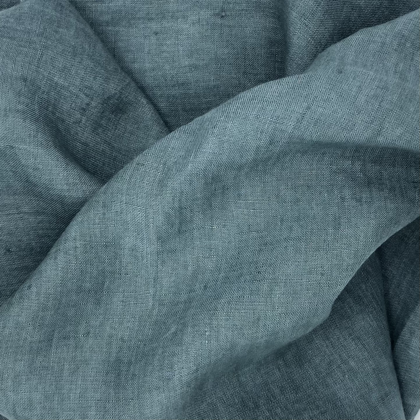 Close-up of a matte sage green fabric with large wavy folds