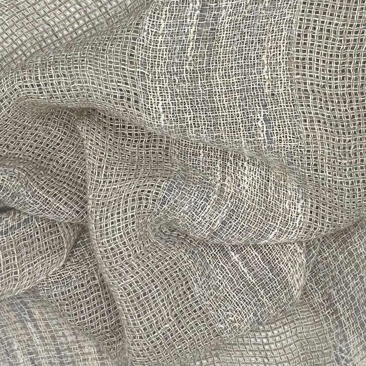 Light gray fabric highlighting the texture of the weave and the variations in thread thickness, contributing to the uneven shading.